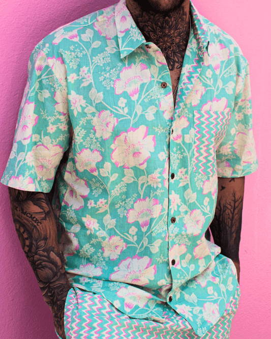 PADMA Short Sleeve Shirt Neon Bloom worn by a man, featuring floral patterns against a vibrant pink background.