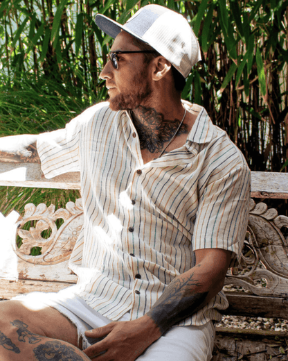 A man wearing an AMBE Short Sleeve Shirt in a tropical setting, exuding casual style and comfort.