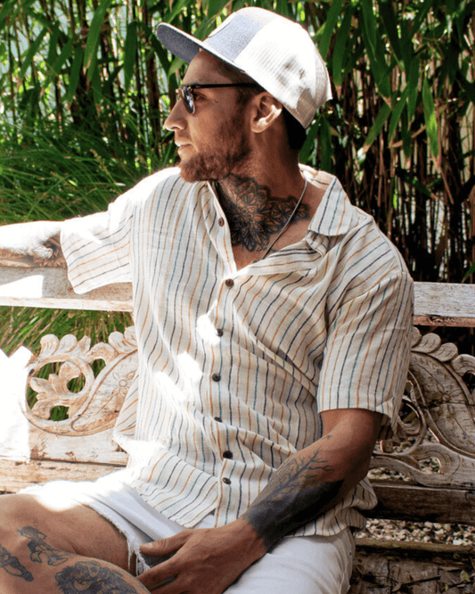 A man wearing an AMBE Short Sleeve Shirt in a tropical setting, exuding casual style and comfort.