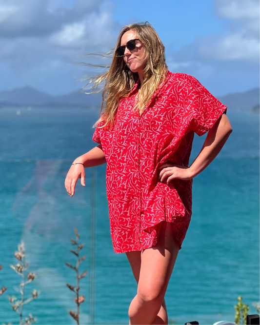 Model wearing ALBA Maxi Shirt in Berry Bloom by the seaside with sunglasses and flowing hair.