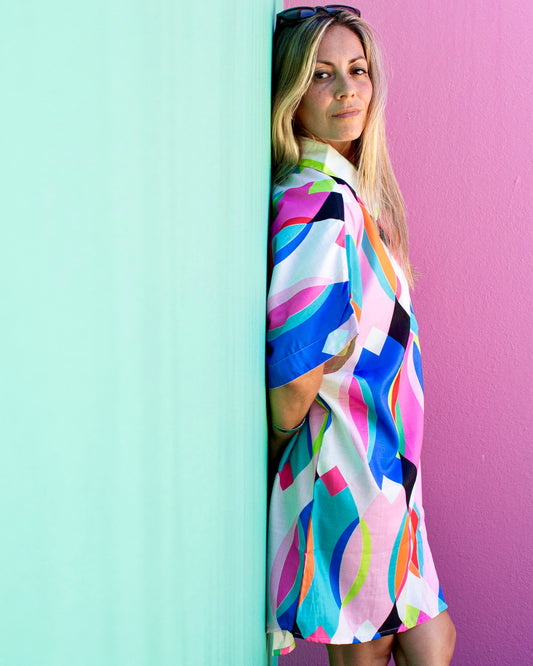 Model wearing the ALBA Maxi Shirt in colorful patterns against a vibrant wall.