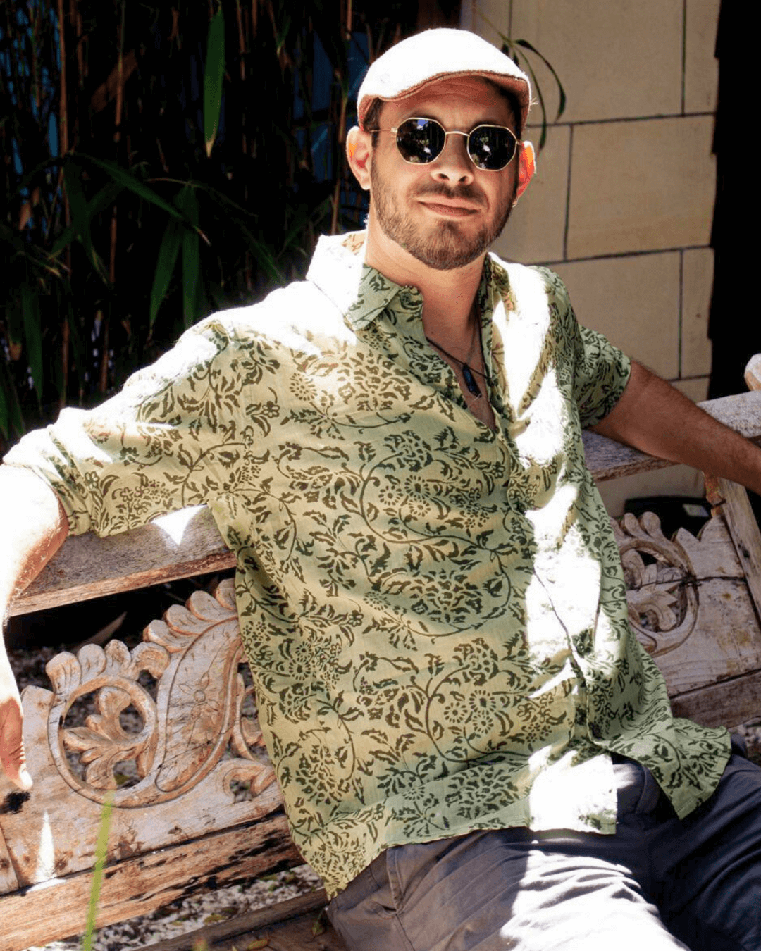 Man wearing SAIRA Long Sleeve Shirt in Florence Green, sitting on a wooden bench with sunglasses.