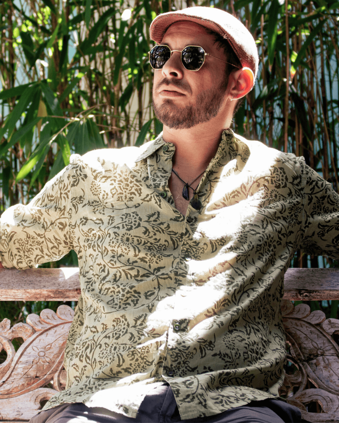 SAIRA Long Sleeve Shirt in Florence Green worn by a man sitting outdoors with a relaxed expression and sunglasses — The Cocoon Way