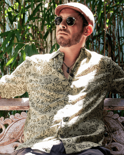SAIRA Long Sleeve Shirt in Florence Green worn by a man sitting outdoors with a relaxed expression and sunglasses — The Cocoon Way