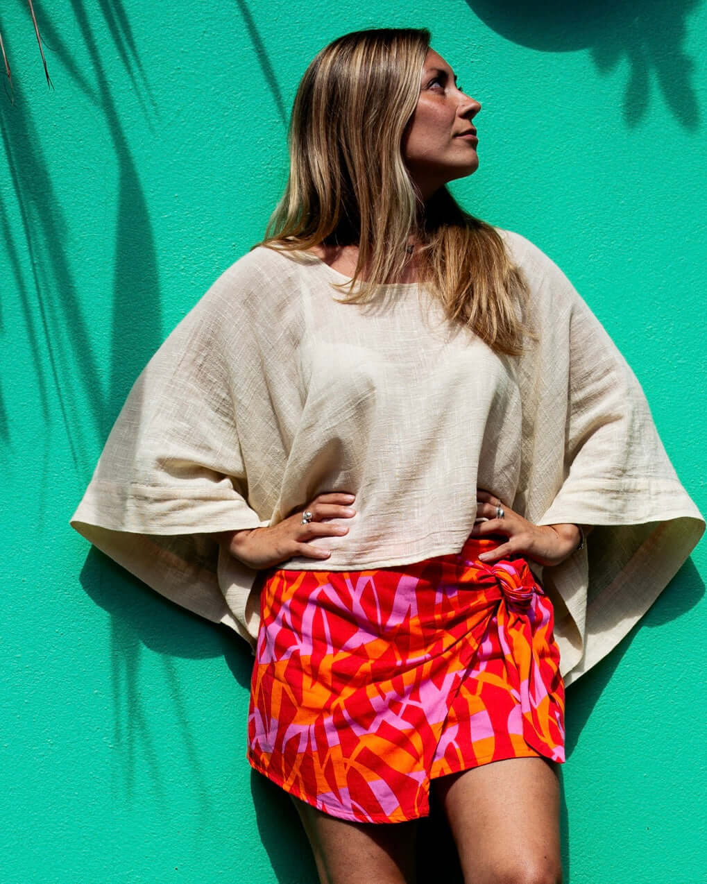 Model wearing VERA Skort in Fuchsia Flame against a vibrant green background, showcasing its stylish design — The Cocoon Way
