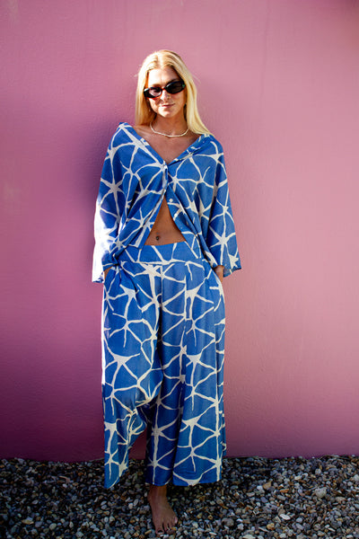Model wearing SOFY Pants with a stylish top against a pink background, showcasing a chic and comfortable outfit.