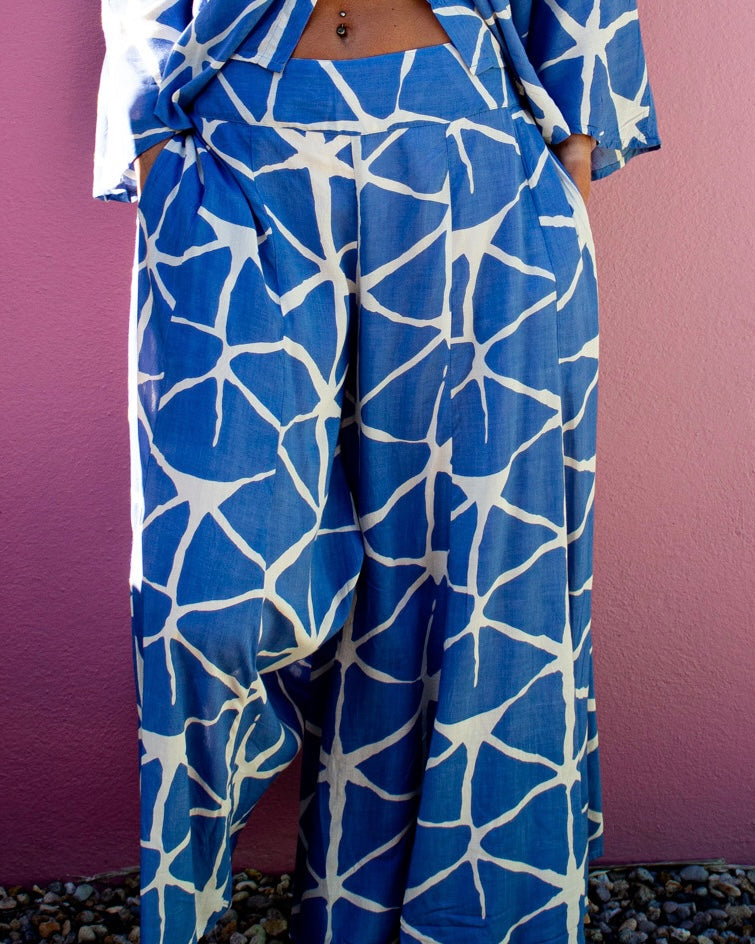 Model wearing SOFY Pants, showcasing blue patterned fabric and a flowy design against a pink background — The Cocoon Way