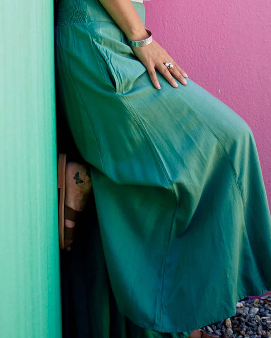 SOFY Pants in teal color, showcasing a fluid silhouette with a wide leg and elastic waistband against a colorful backdrop.