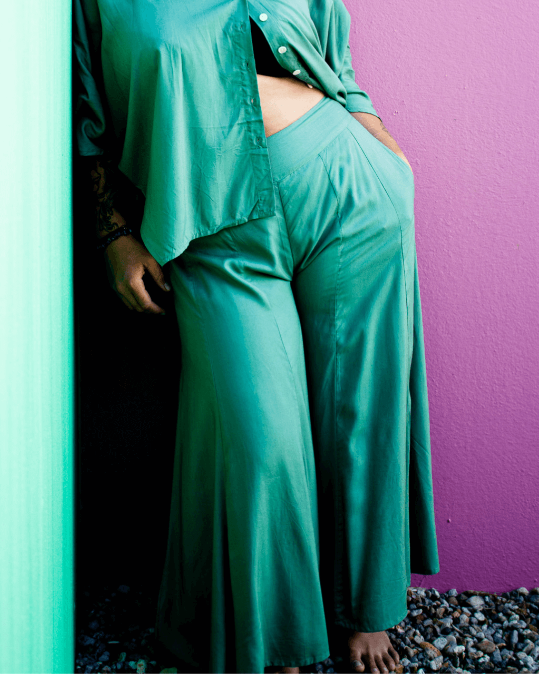 Close-up of model wearing SOFY Pants in teal color, showcasing wide legs and a relaxed fit against a colorful backdrop.