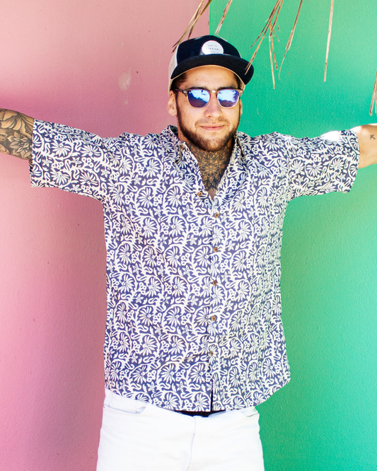 Man wearing a patterned shirt and sunglasses with a colorful background