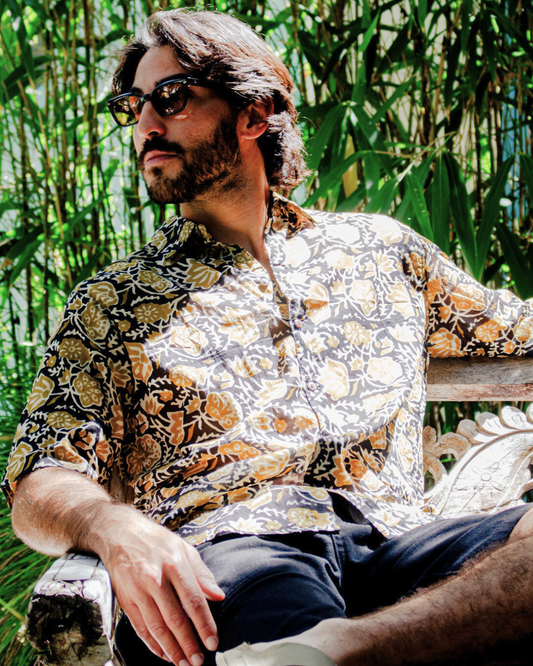 Man wearing SAIRA Short Sleeve Shirt seated among greenery, showcasing its stylish design and comfortable fit — The Cocoon Way