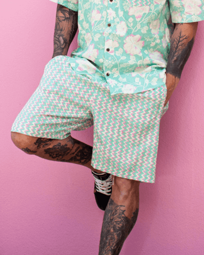 PADMA Cotton Shorts in neon bloom pattern worn with a floral shirt against a pink background — The Cocoon Way