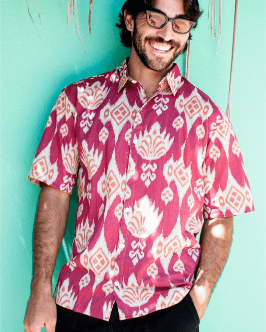 PADMA Short Sleeve Shirt Cherry Ikat worn by a smiling man against a vibrant green background.
