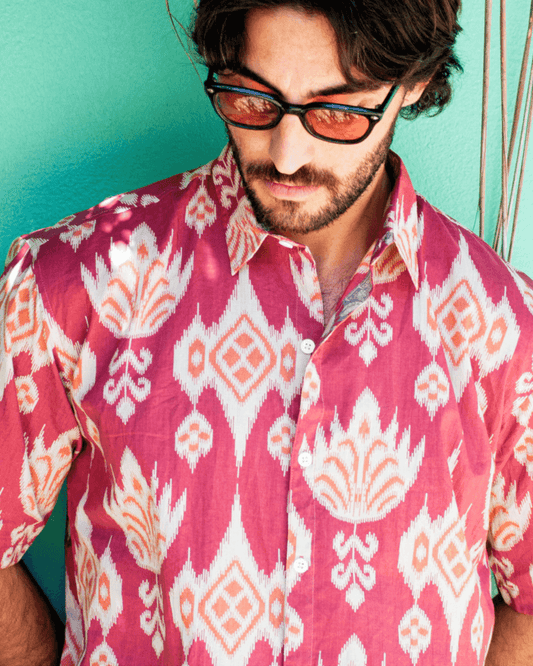 Model wearing PADMA Short Sleeve Shirt Cherry Ikat with vibrant patterns against a colorful background.