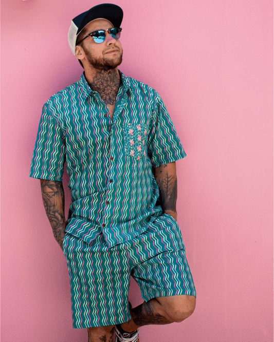 Man wearing PADMA Short Sleeve Shirt Neon Wave with vibrant colors against a pink background — The Cocoon Way