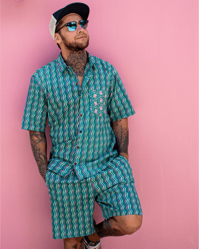 Man wearing PADMA Short Sleeve Shirt Neon Wave with vibrant colors against a pink background.