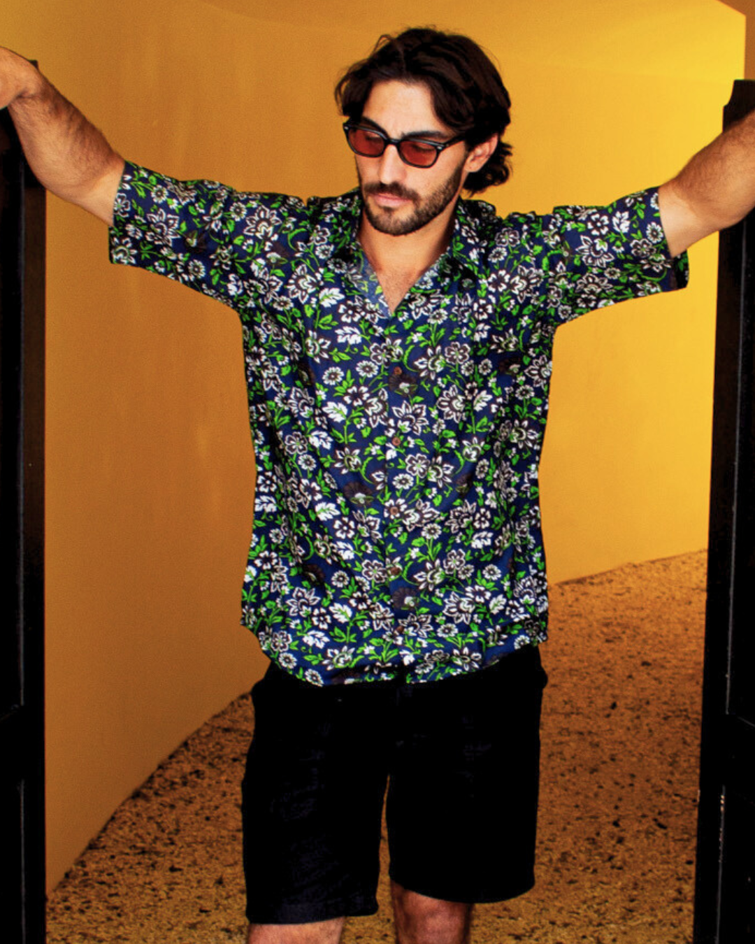 Man wearing PADMA Short Sleeve Shirt Night Flower in a stylish pose with sunglasses.