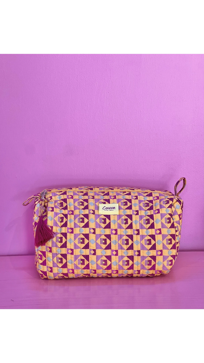 The Cocoon Way Niwas large quilted cotton pouch in a geometric purple and yellow print with a tassel zip pull.