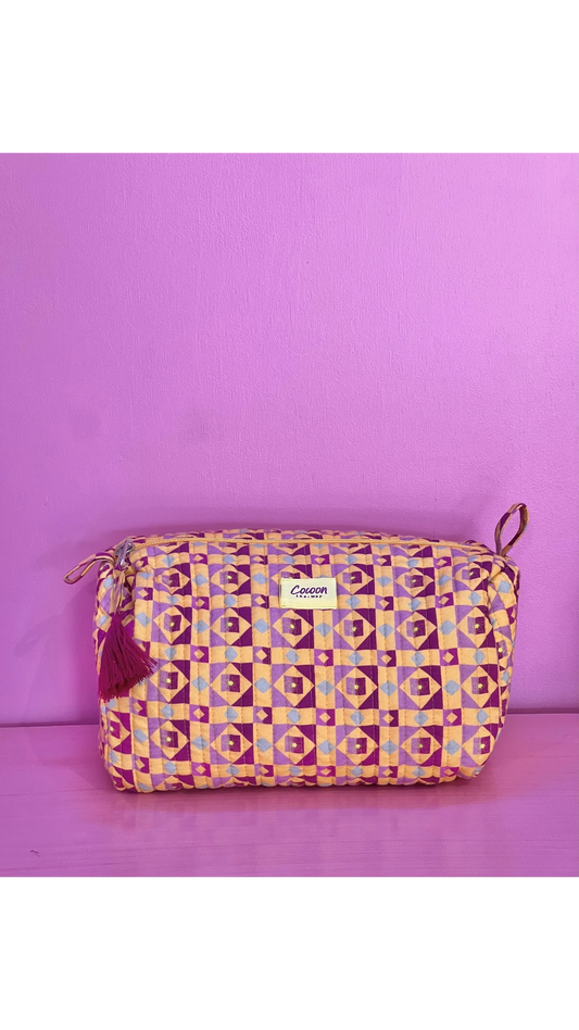 The Cocoon Way Niwas large quilted cotton pouch in a geometric purple and yellow print with a tassel zip pull.